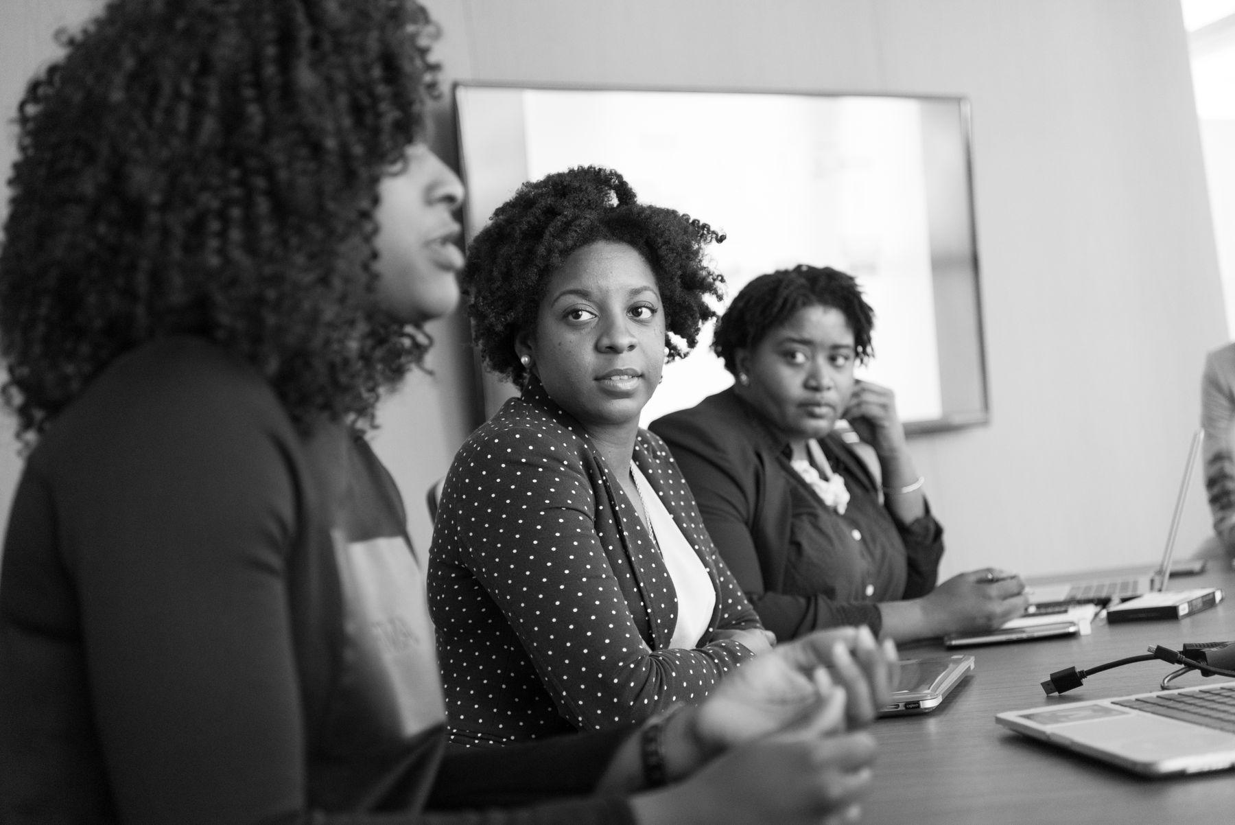 Three women discussing work around a table